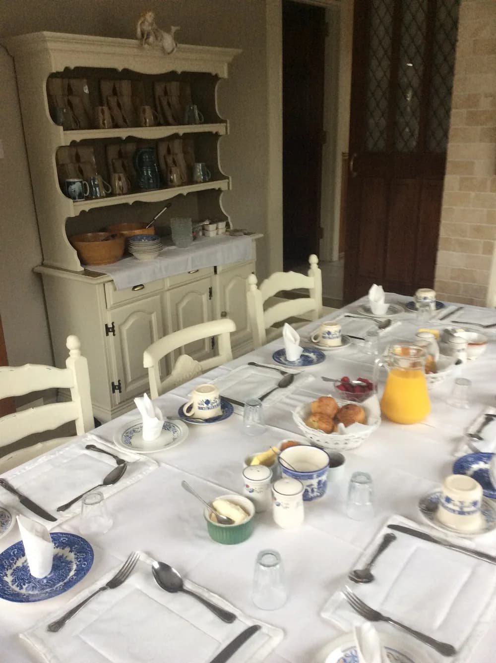 The breakfast table set with blue and white china, pastries, fruit and orange juice
