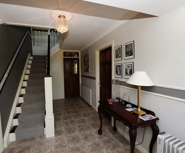 The entrance hall, with the staircase, a console table and family photographs