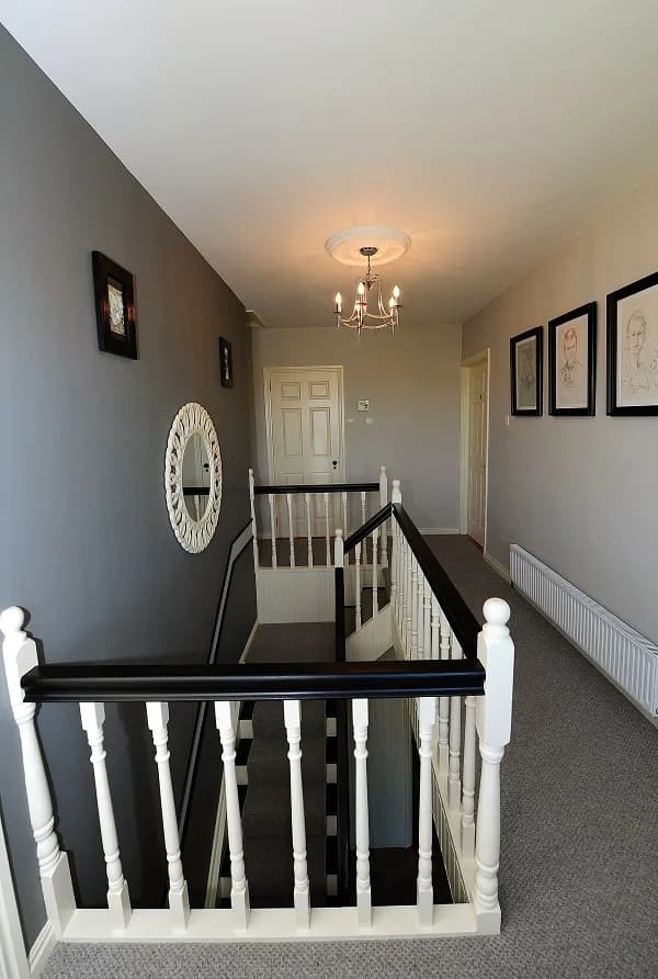 The upstairs landing, with a painted balustrade and framed drawings