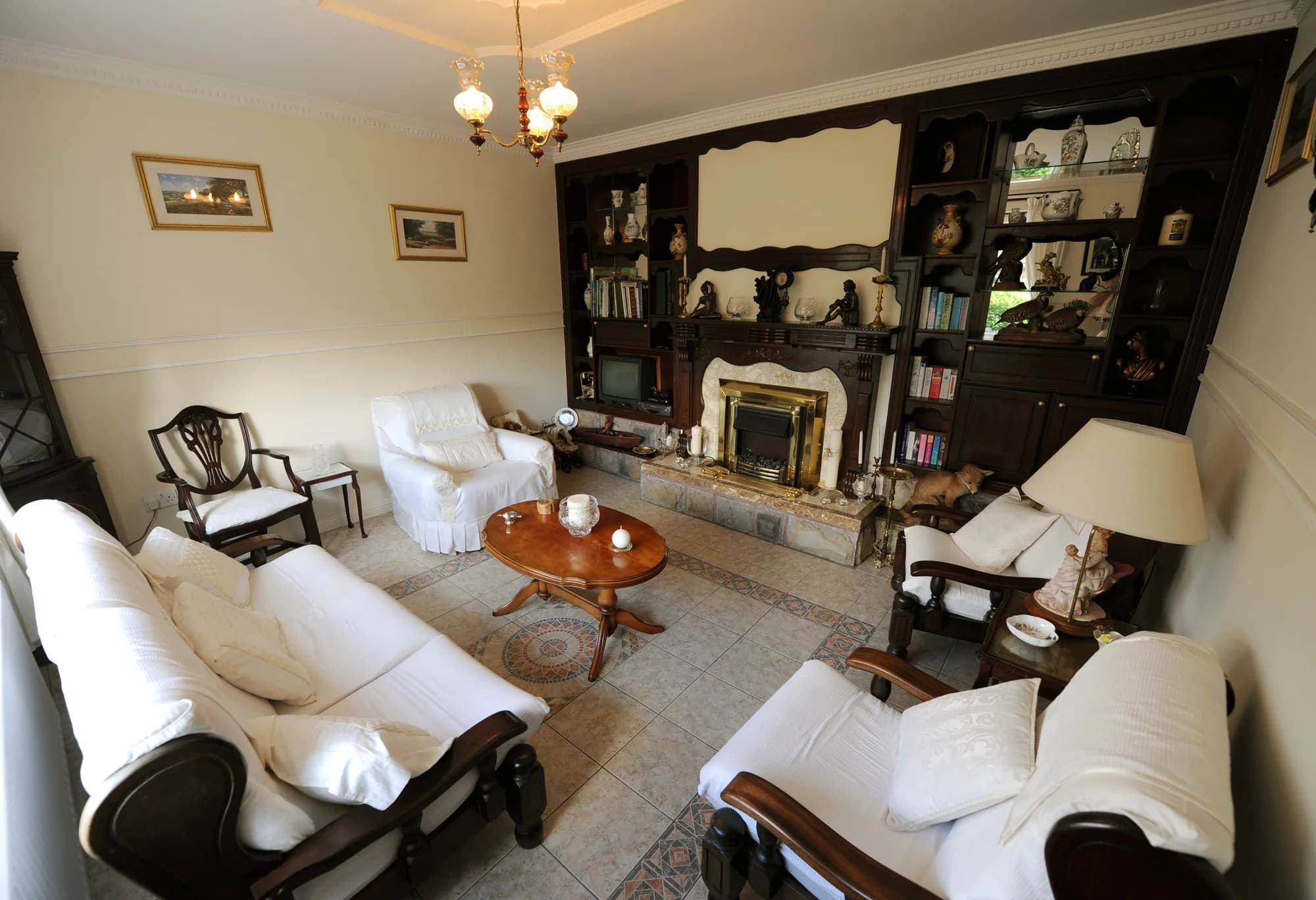 The guest reading room with an open fire, bookshelves and white upholstered seating