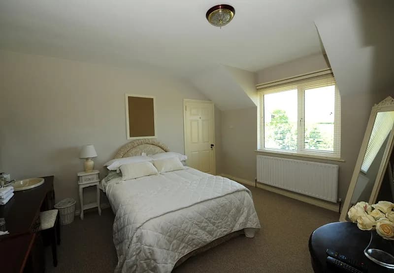 Room 1, a double room with a cream upholstered headboard and a window over the garden