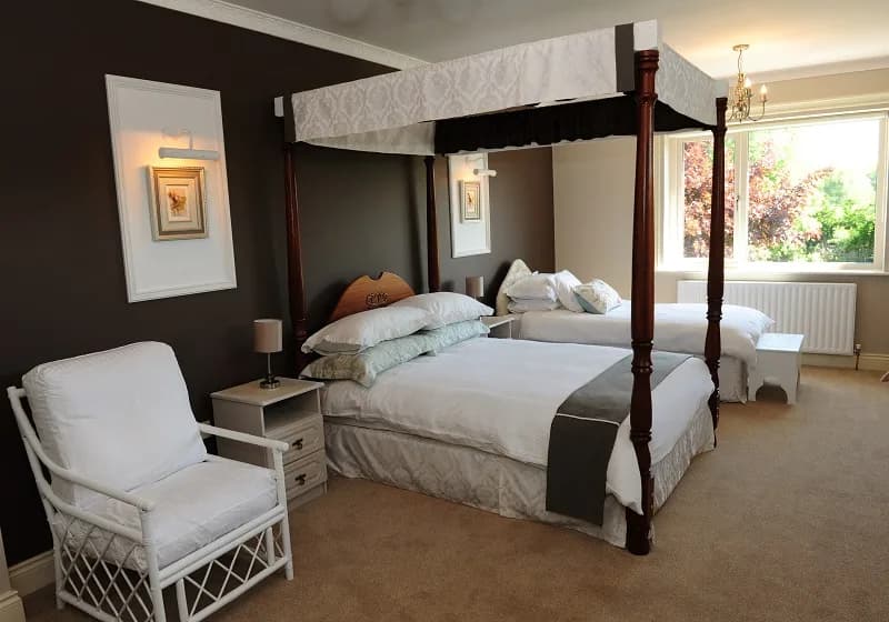 Room 4 showing the four poster bed, the single bed and a wicker armchair