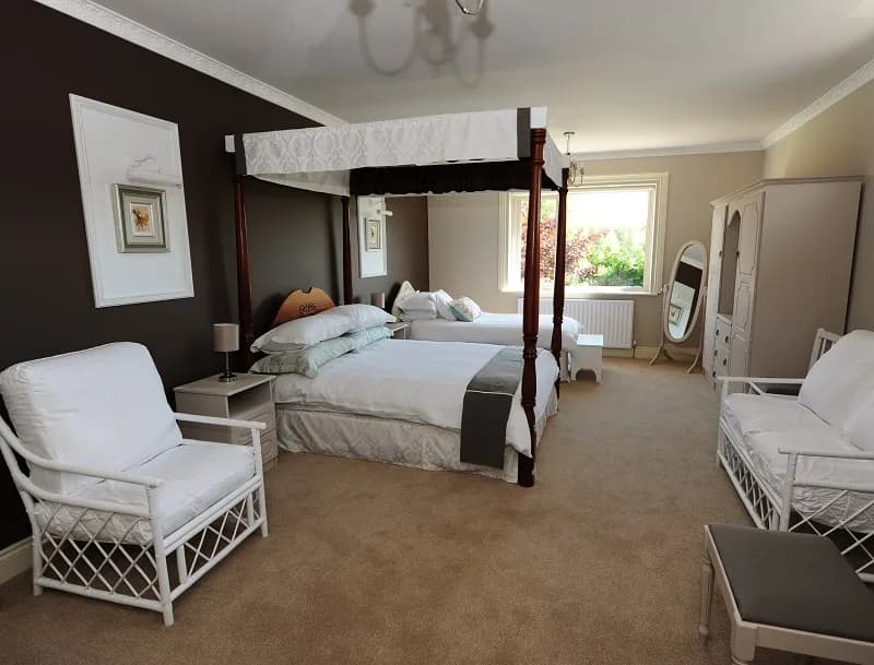 Room 4 in full, with two armchairs, a stool and the four poster bed